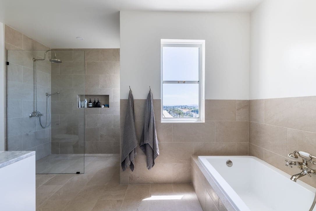 Bathroom with a glass walk-in shower, soaking tub, and a window overlooking the city